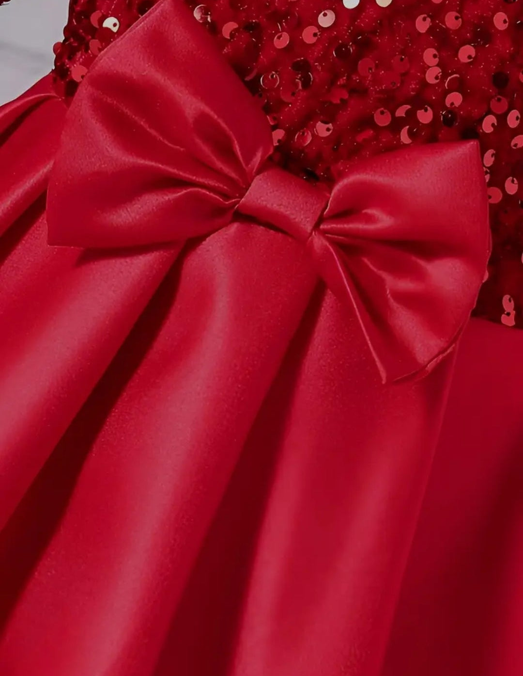 Avondjurk met pailletten bovenzijde en en wijde rok van satijnen stof. Met een grote strik aan de voorzijde. In crème en rood leverbaar.