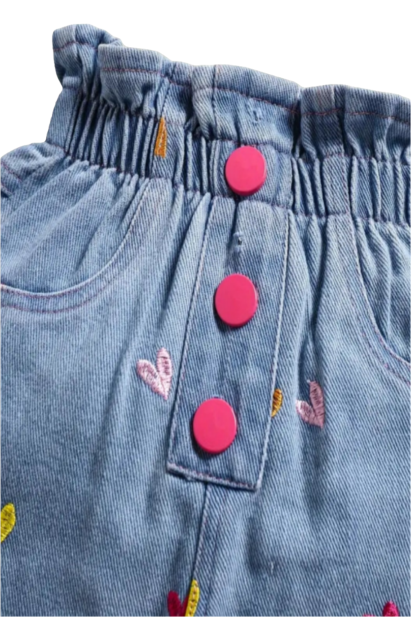 Denim jeans met gekleurde hartjes en roze knoopjes (leuk te combineren met bijpassend jack).En de roze gympjes.