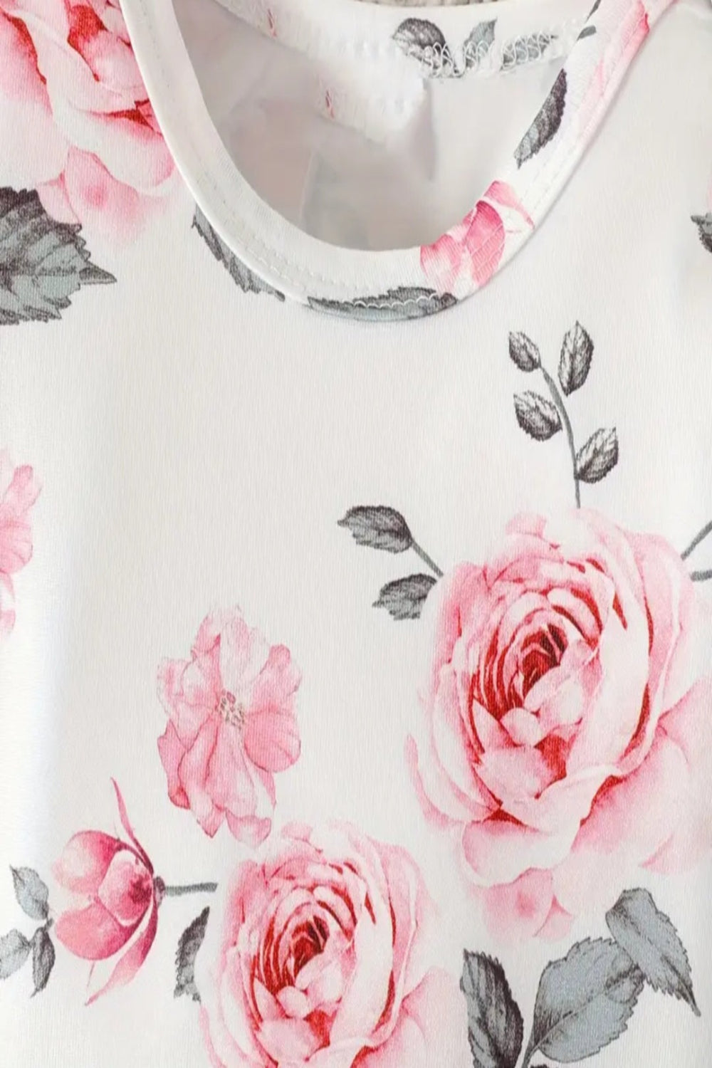 witte body met lange mouw met roze rozen en roze gilet en donkere  jeans met bijpassend riem