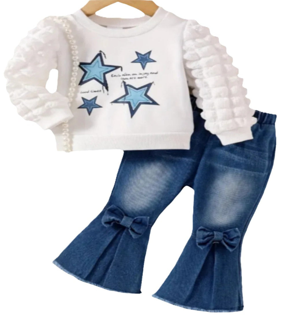 witte trui met blauwe sterren met mooi bewerkte mouwen  en jeans met strikjes en wijde pijpen 